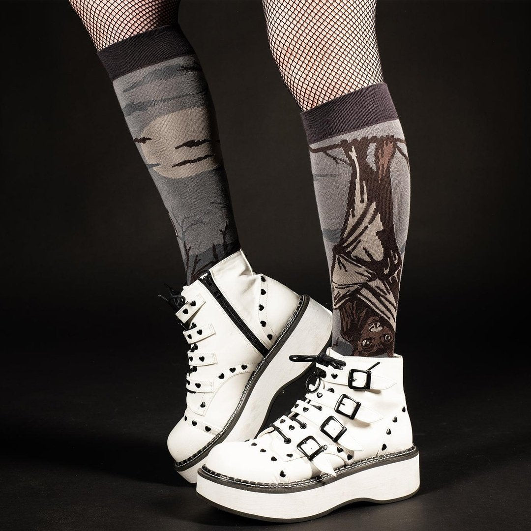 White platform boots worn with patterned fishnet stockings on a black background