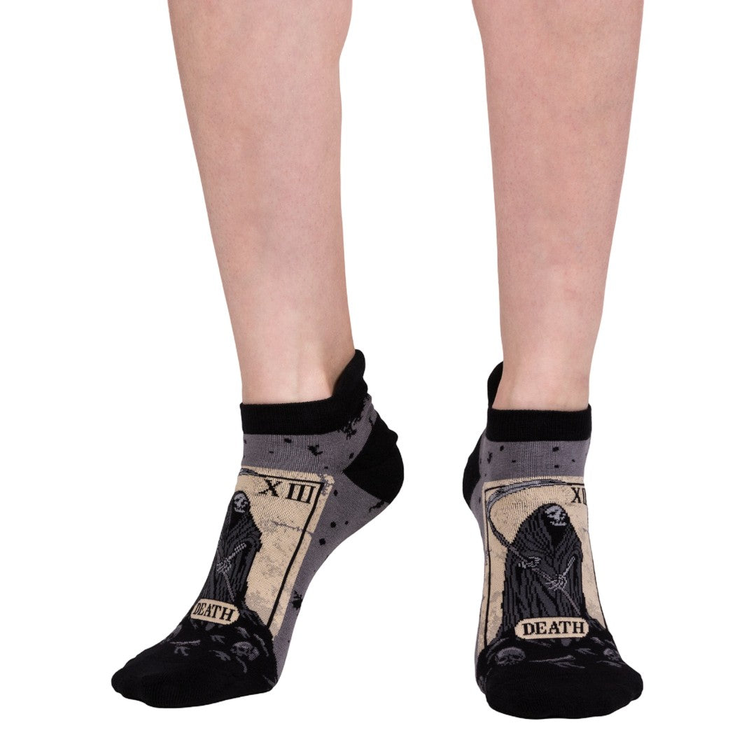 Black socks with 'Death' tarot card design worn by a person on a white background