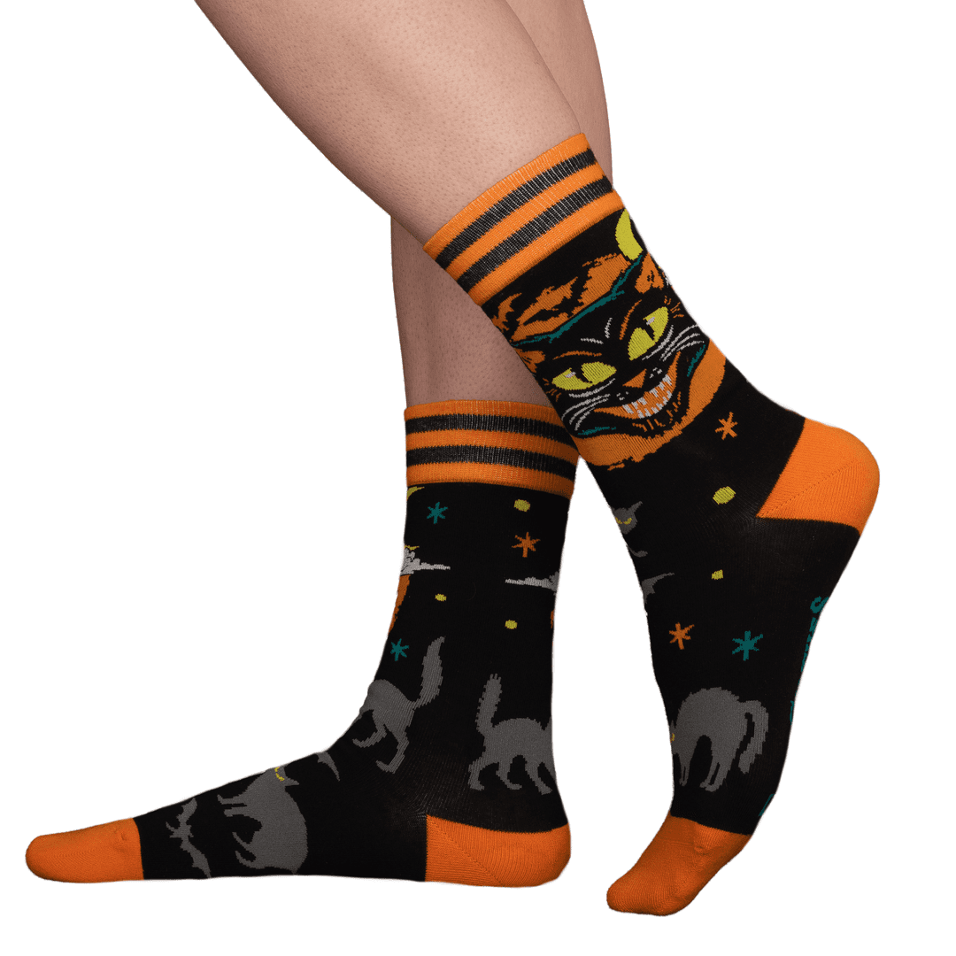 Halloween-themed socks with black cats, pumpkins, and stars on a white background