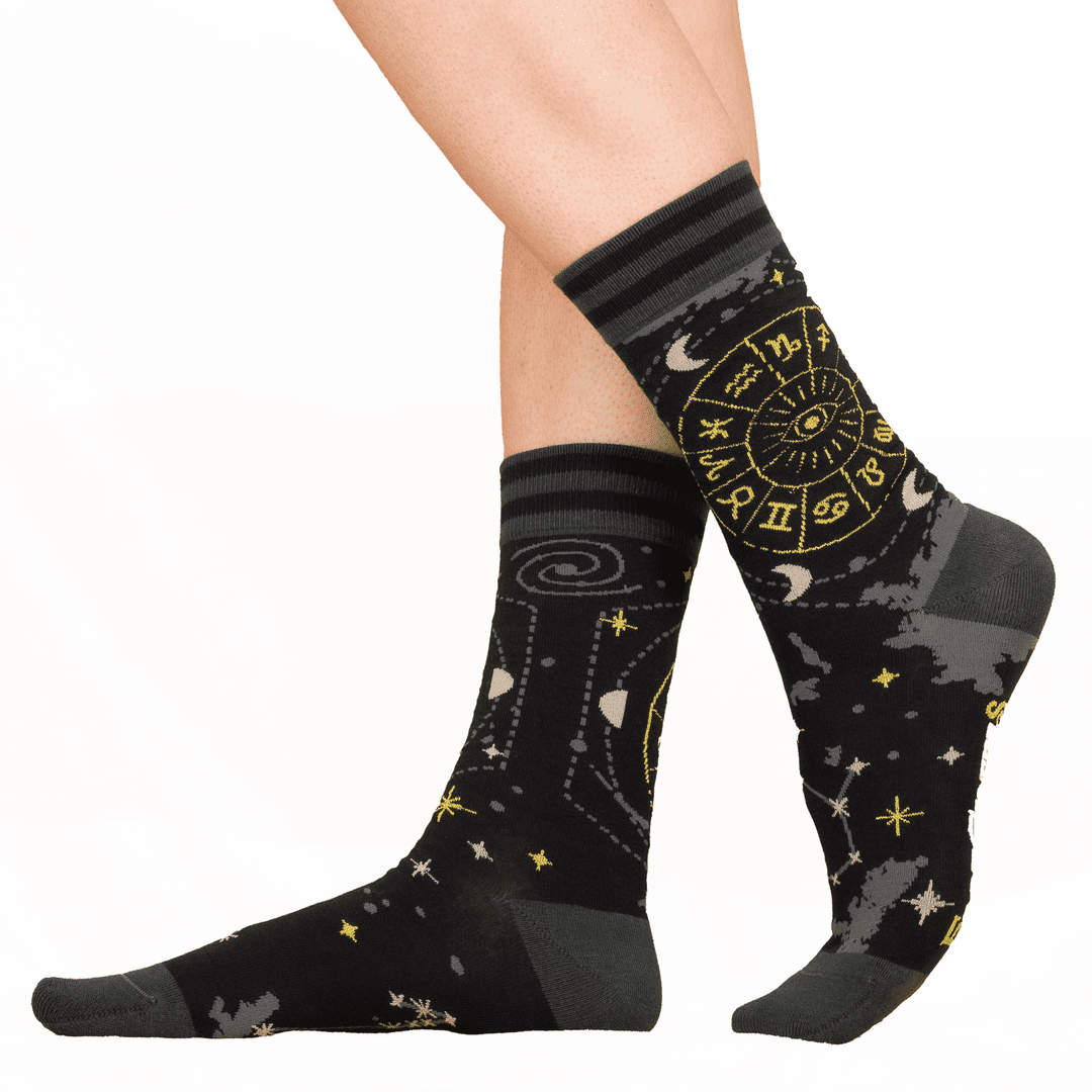 Black socks with star and moon patterns worn by a person on a white background