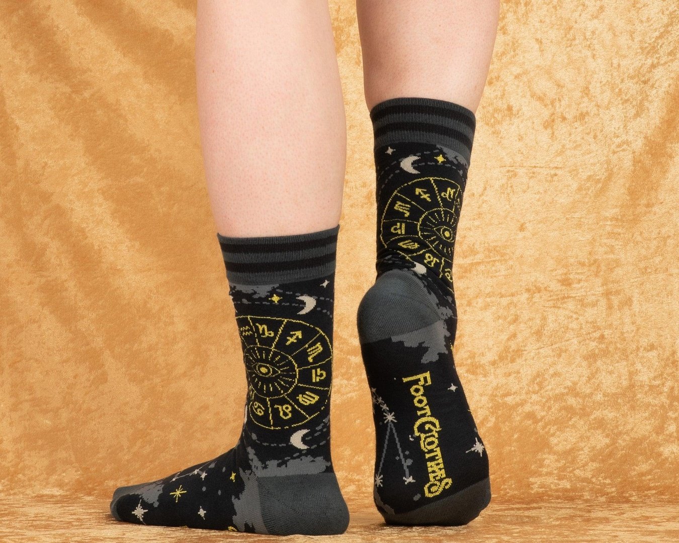 Black socks with yellow designs worn by a person on a beige background