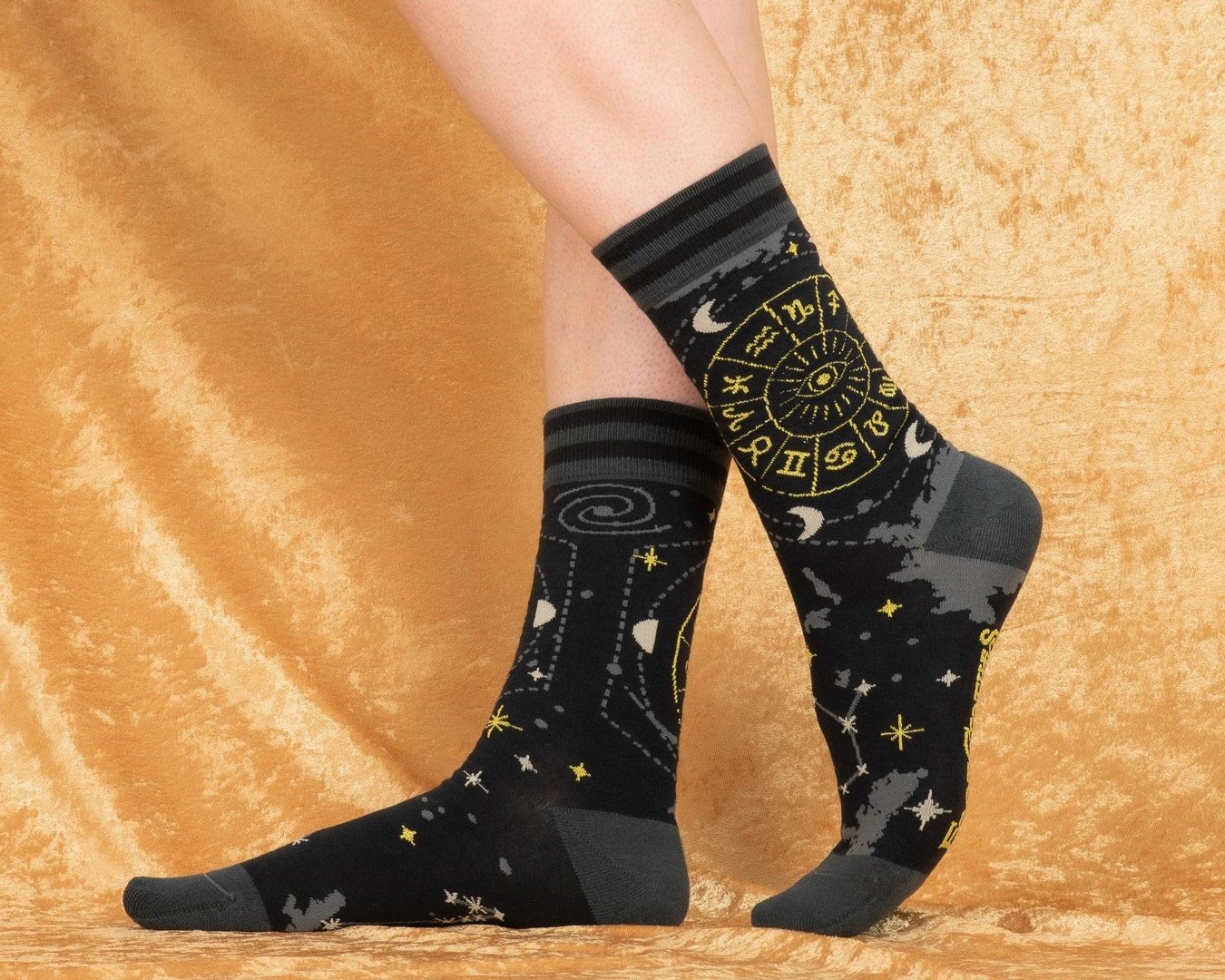Black socks with star and moon patterns worn by a person on a beige background