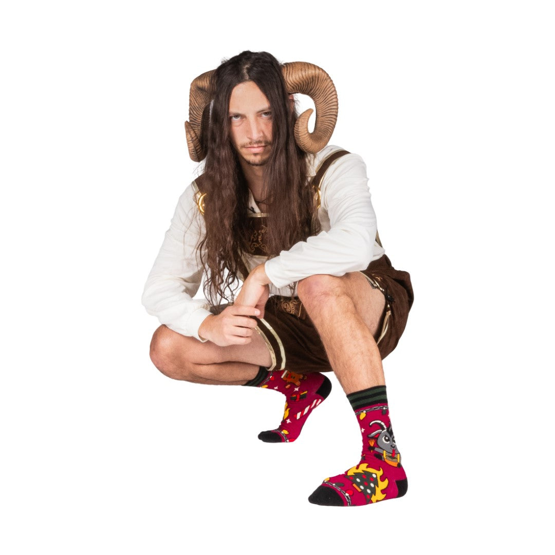Person wearing a costume with ram horns and colorful socks on a white background