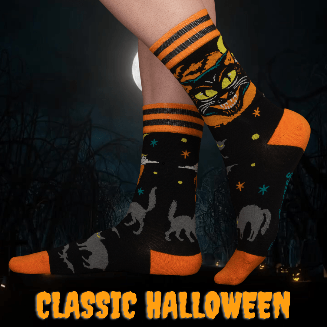Halloween-themed socks with black cats and orange accents against a dark background.