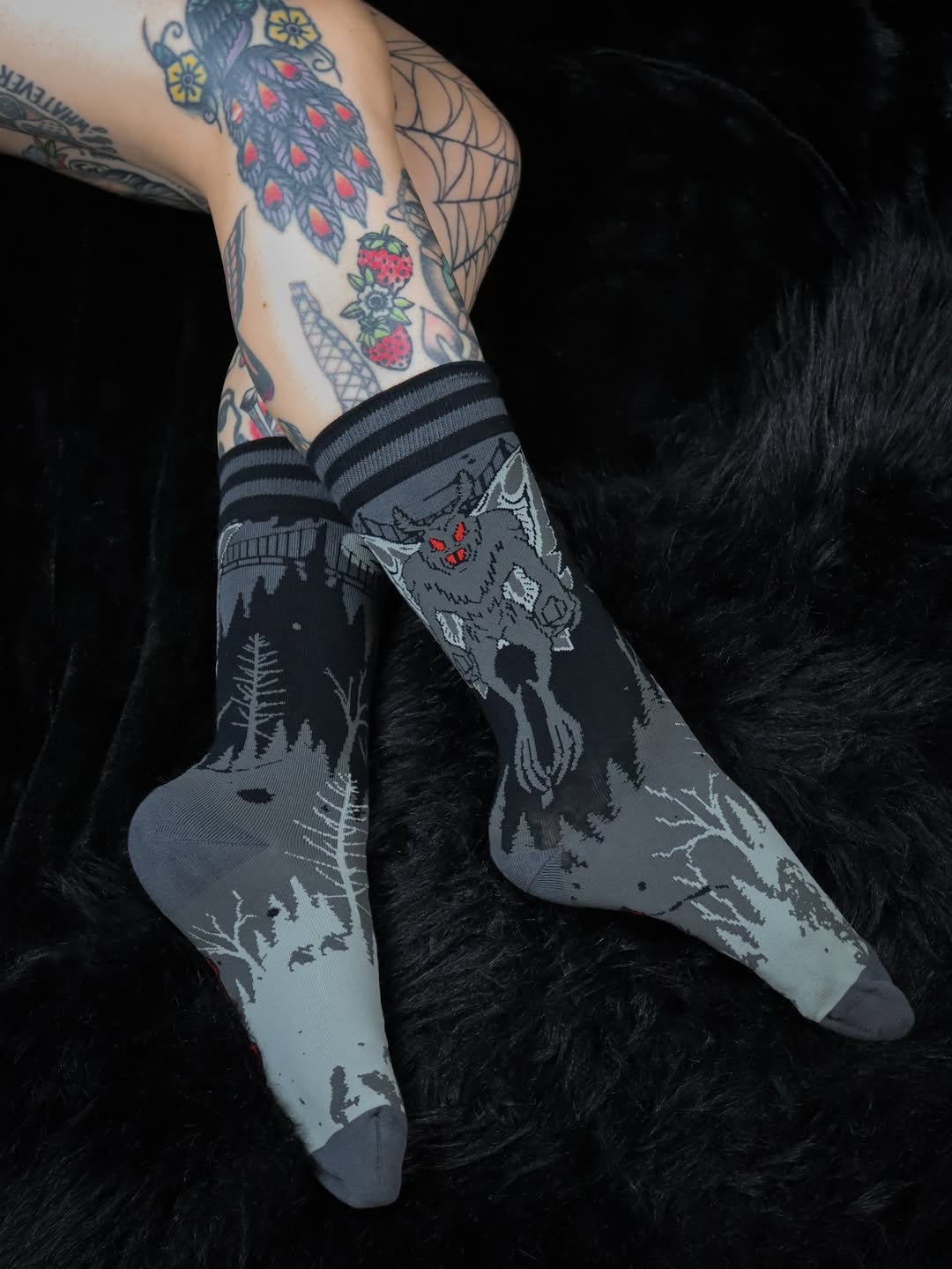 Tattooed legs wearing black and gray patterned socks on a dark background