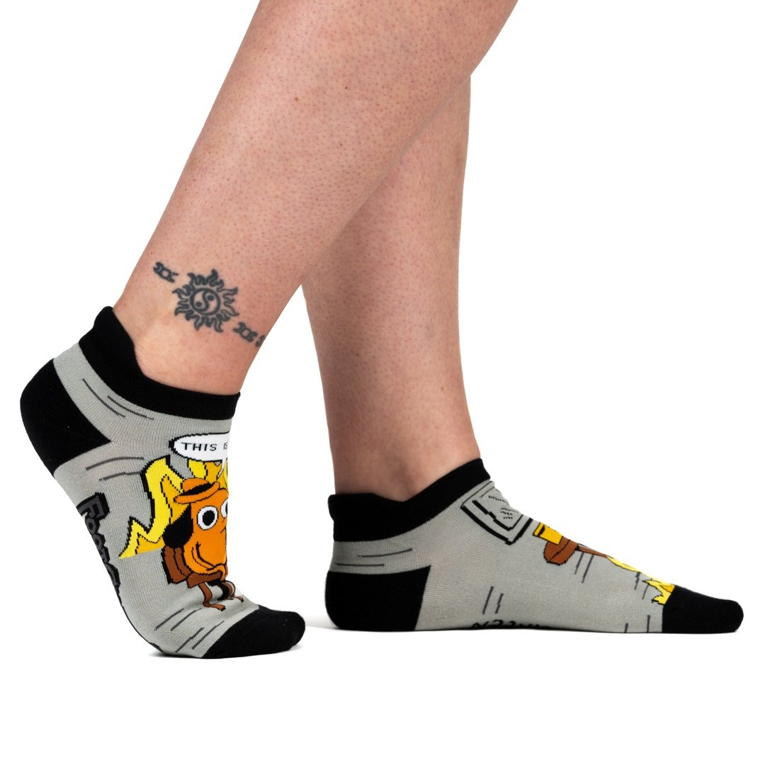 Gray socks with cartoon character design worn by a person on a white background