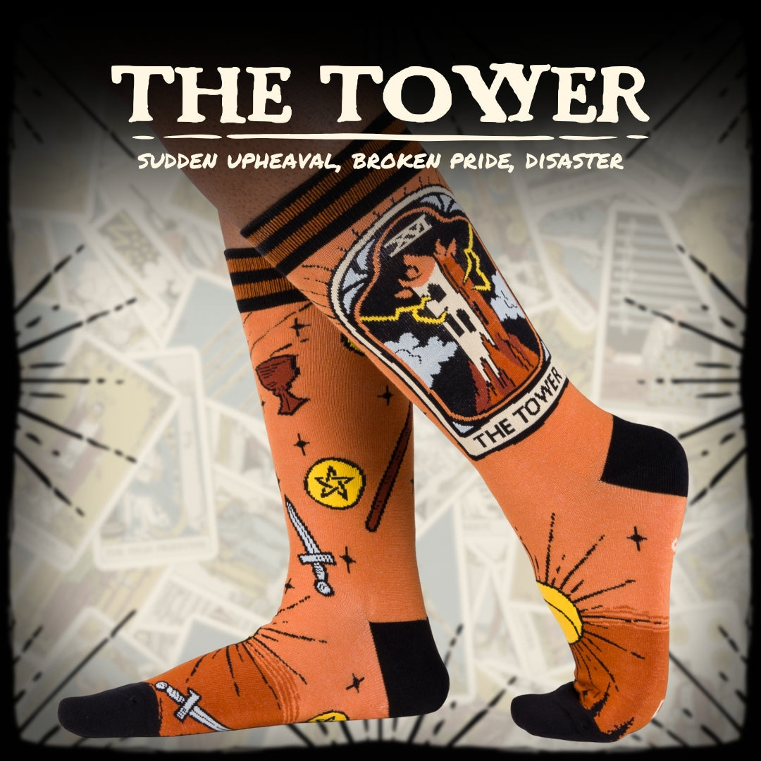Orange socks with tarot card design labeled 'The Tower' on a stylized background.