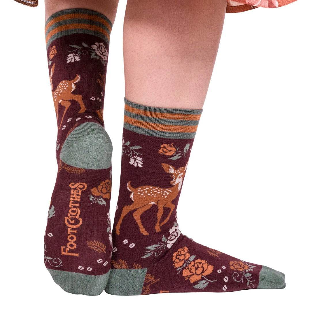 Maroon socks with deer and floral patterns worn by a person on a white background