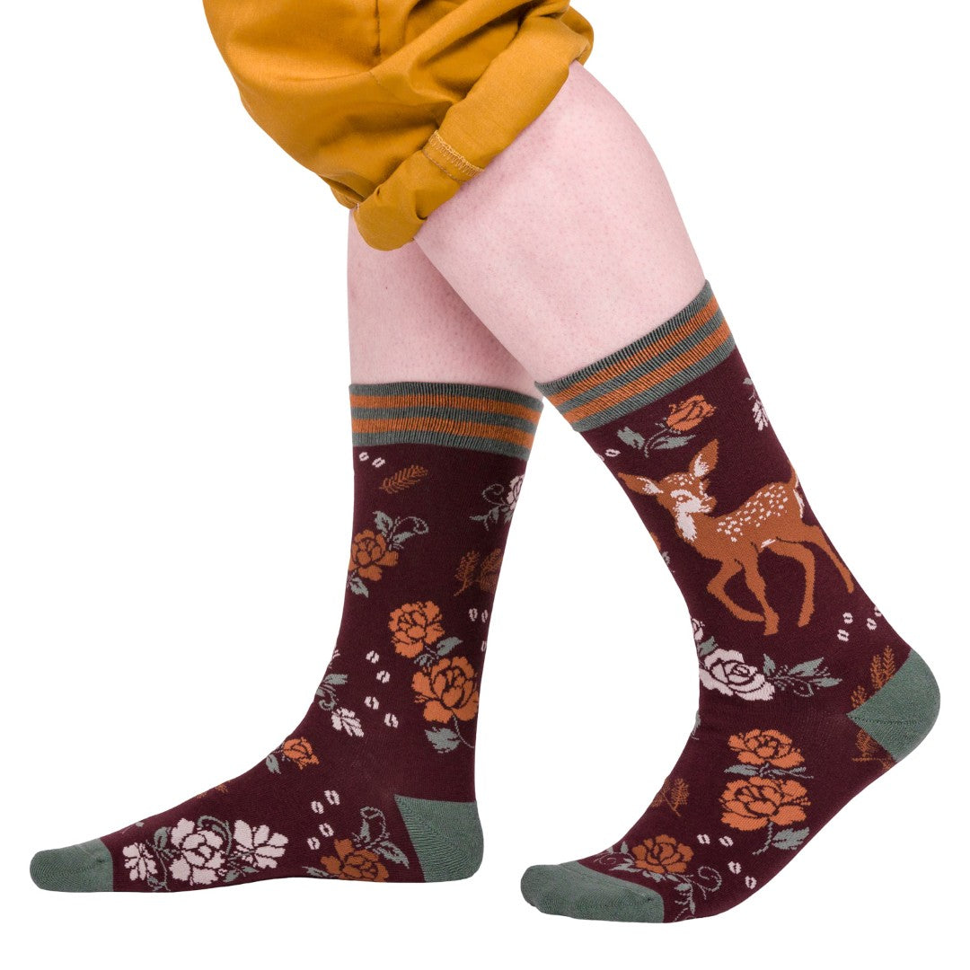 Maroon socks with deer and floral patterns worn by a person on a white background