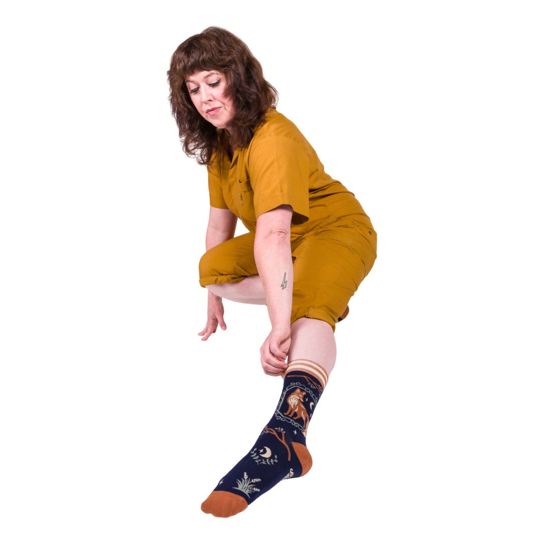Person wearing mustard yellow outfit and patterned socks on a white background