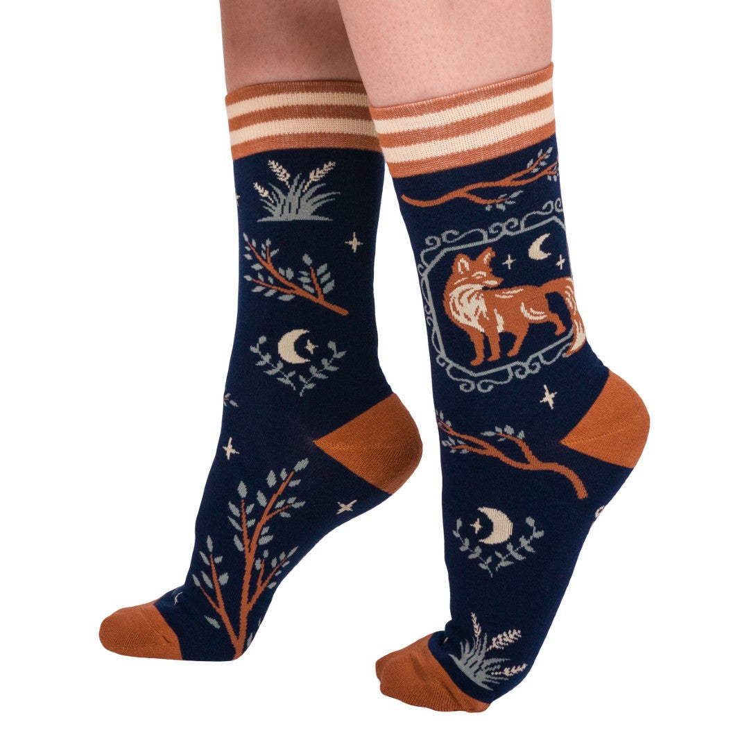 Navy blue socks with fox and moon design worn by a person on a white background