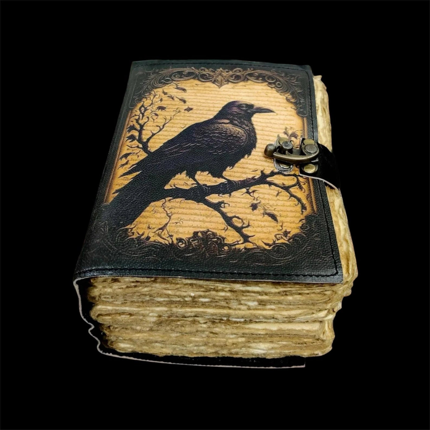 A leather journal on a black background. The cover depicts a drawing of a black crow perched on dark branches.