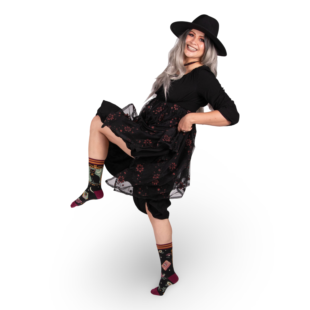 Woman wearing a black dress with floral patterns and a black hat on a white background