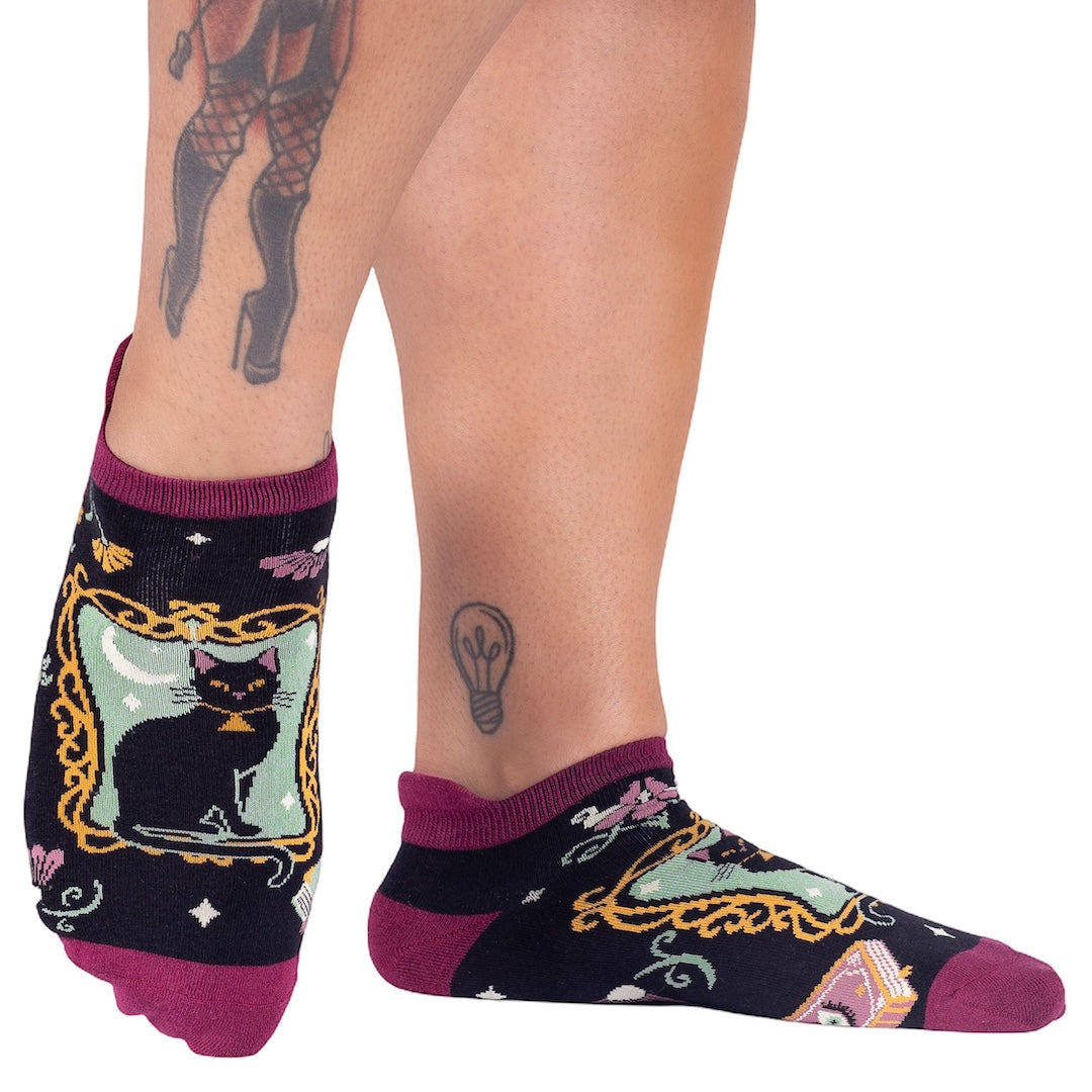 Person wearing socks with black cat design on a white background