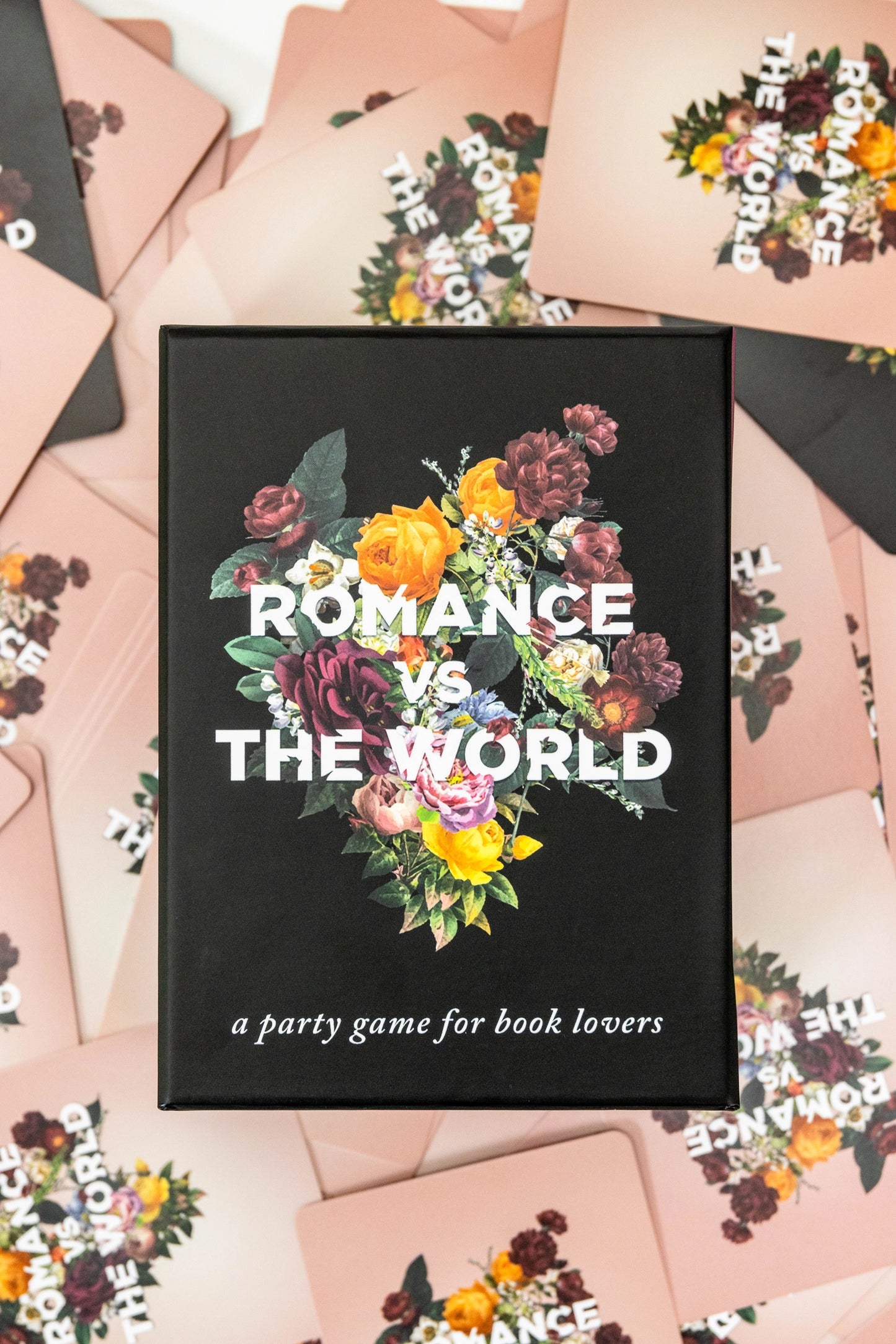 A collection of pink cards piled on a white background, with bouquets of flowers in the center of each. White text says "Romance vs the world." In the center of the image is a black box with a bouquet of flowers in the center. White text says "romance vs the world."