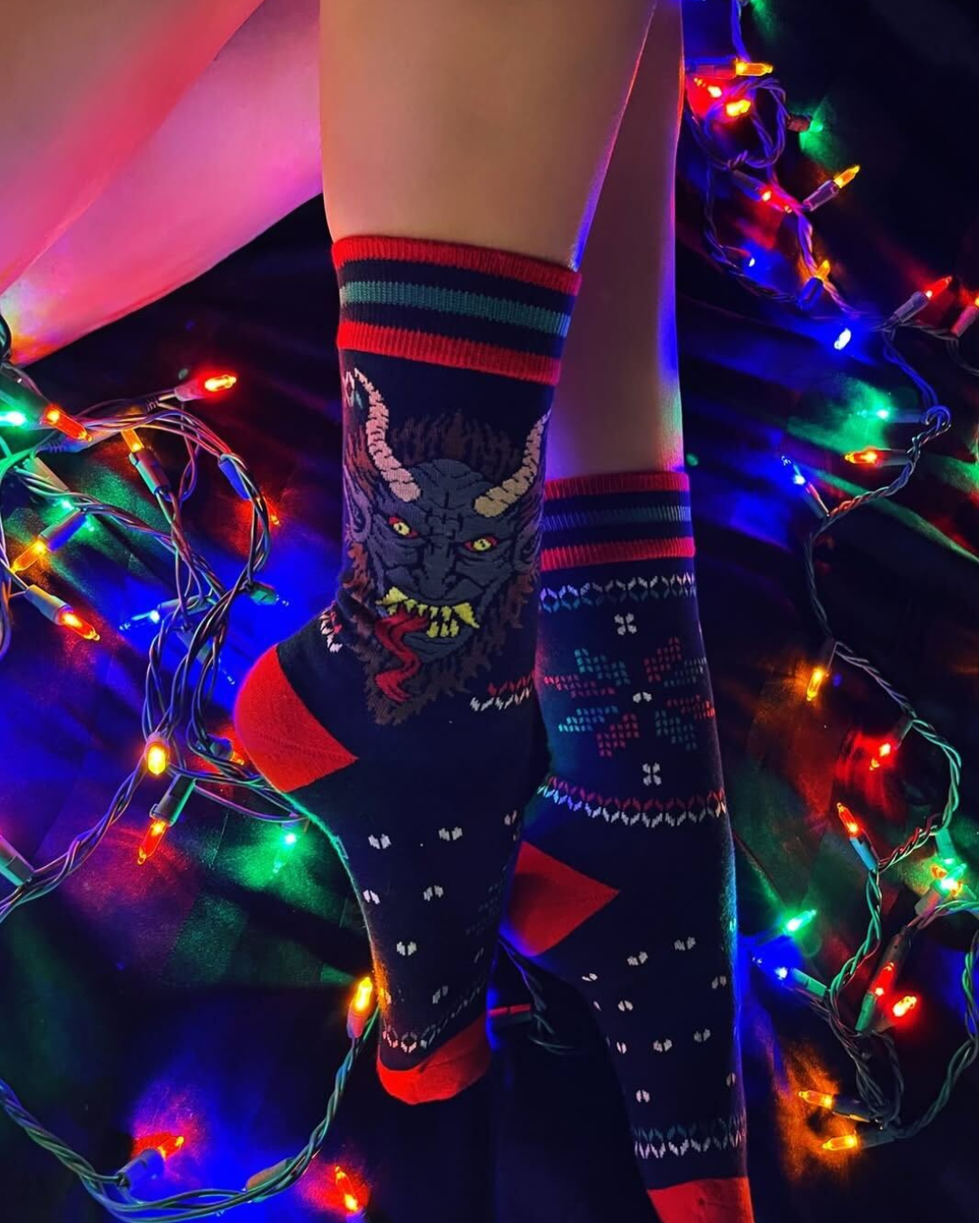 Person wearing colorful patterned socks with decorative lights in the background