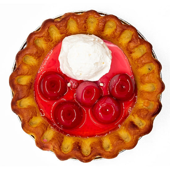 A candle in the shape of a realistic-looking cherry pie, featuring "cherries" and "ice cream" on top and a crust around the center. The candle is in a "pie tin" holder.