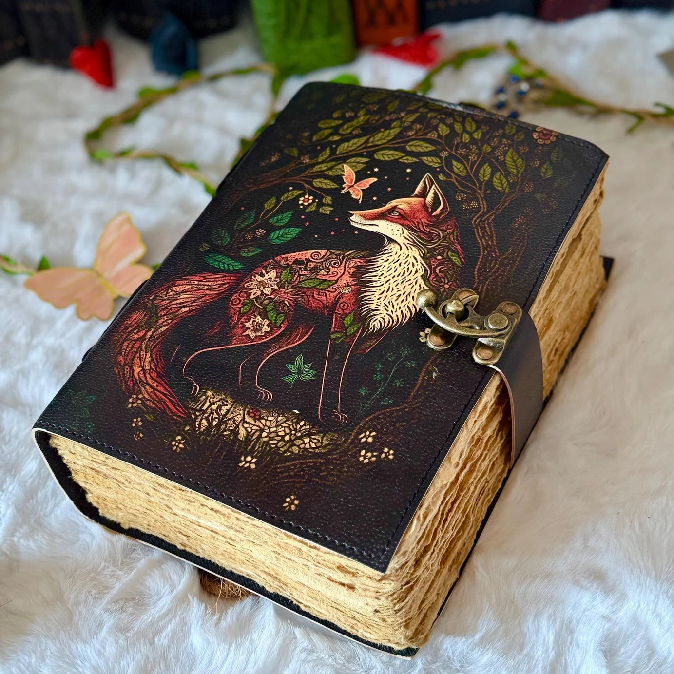 A leather journal on a white cloth. The cover depicts a red and white fox next to a dark forest.