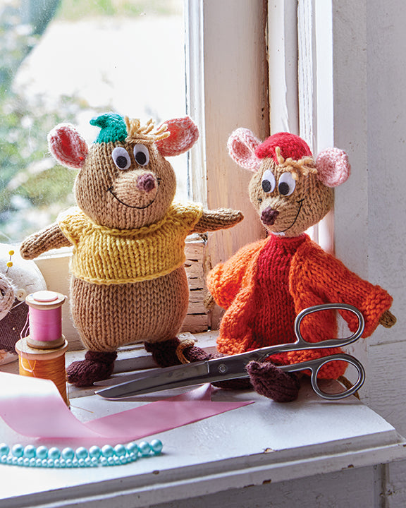 Two knitted mouse toys on a table with scissors and yarn.