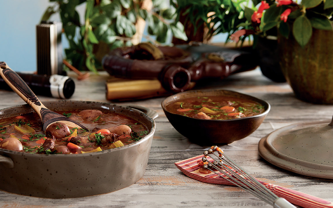 Two bowls of stew on a wooden table with decorative elements.