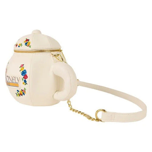 A white purse against a white background. The purse is shaped like a teapot. Around the front are colorful flowers. Gold and blue text says "Dragonfly Inn," with a gold and blue dragonfly next to it. The top of the teapot has a brass zipper. Next to the purse is a white strap, and a gold chain is attached to the front.