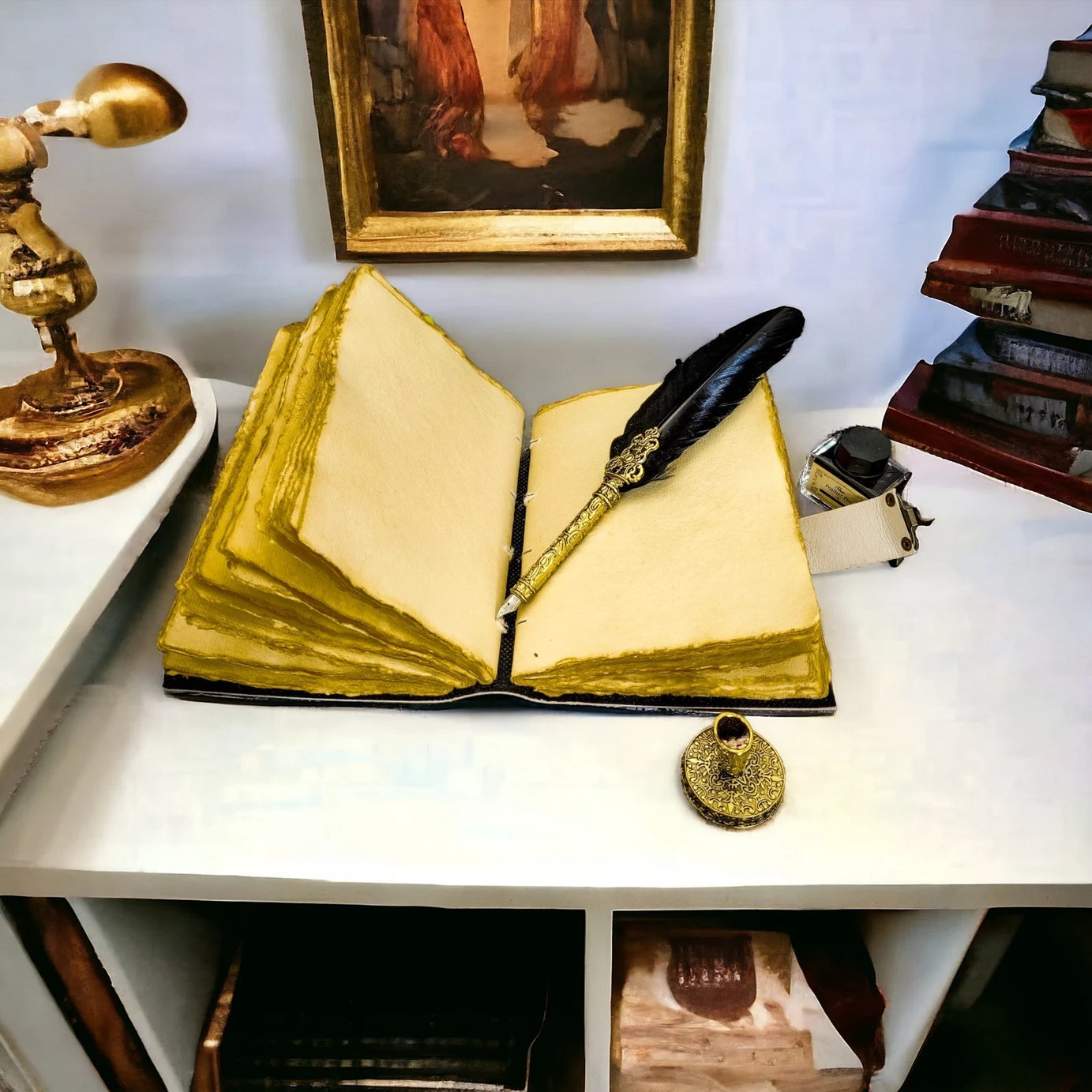 A leather journal on a white table open to show the blank vintage-style pages inside. Sitting on a page is a gold quill pen with a black feather. Next to the journal is a gold lamp, a pile of books, and a bottle of ink.