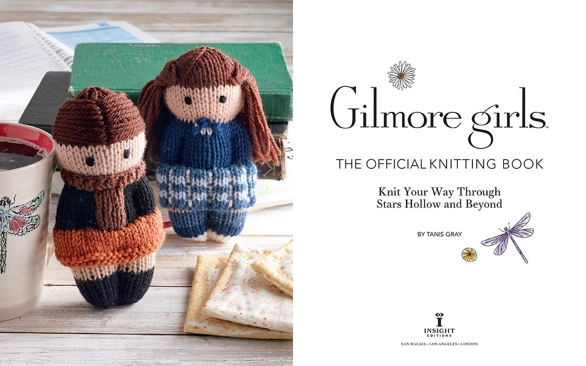 A two-page spread from the book. On the left are two knitted effigies depicting the two main characters from the TV series "Gilmore Girls." Around them are a ceramic coffee mug with a moth on the front, a stack of worn books, a day planner, and a pile of frosted pop-tarts. On the right is the book's title page. Black text says "Gilmore girls. The official knitting book. Knit your way through stars hollow and beyond."