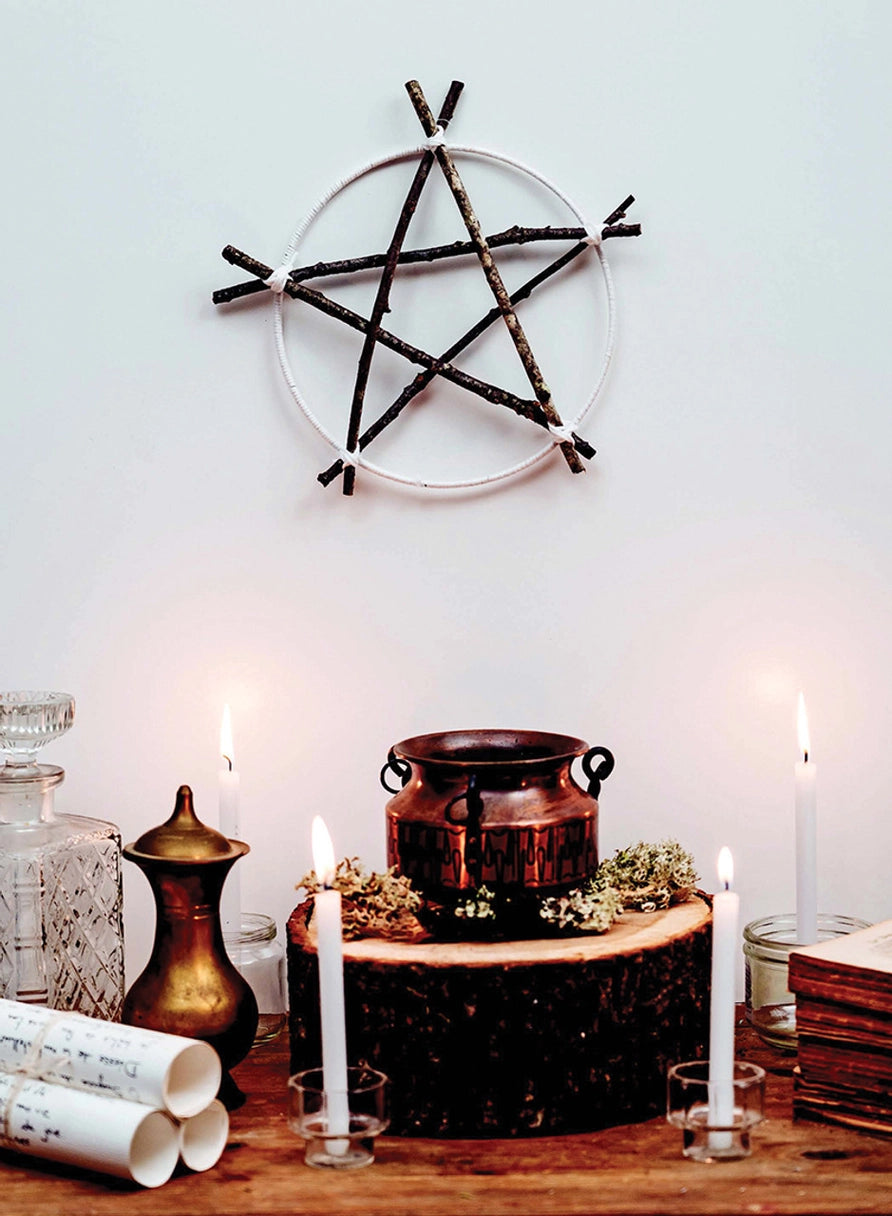 A pentagram made of wooden stiicks above an incense pot and candles.