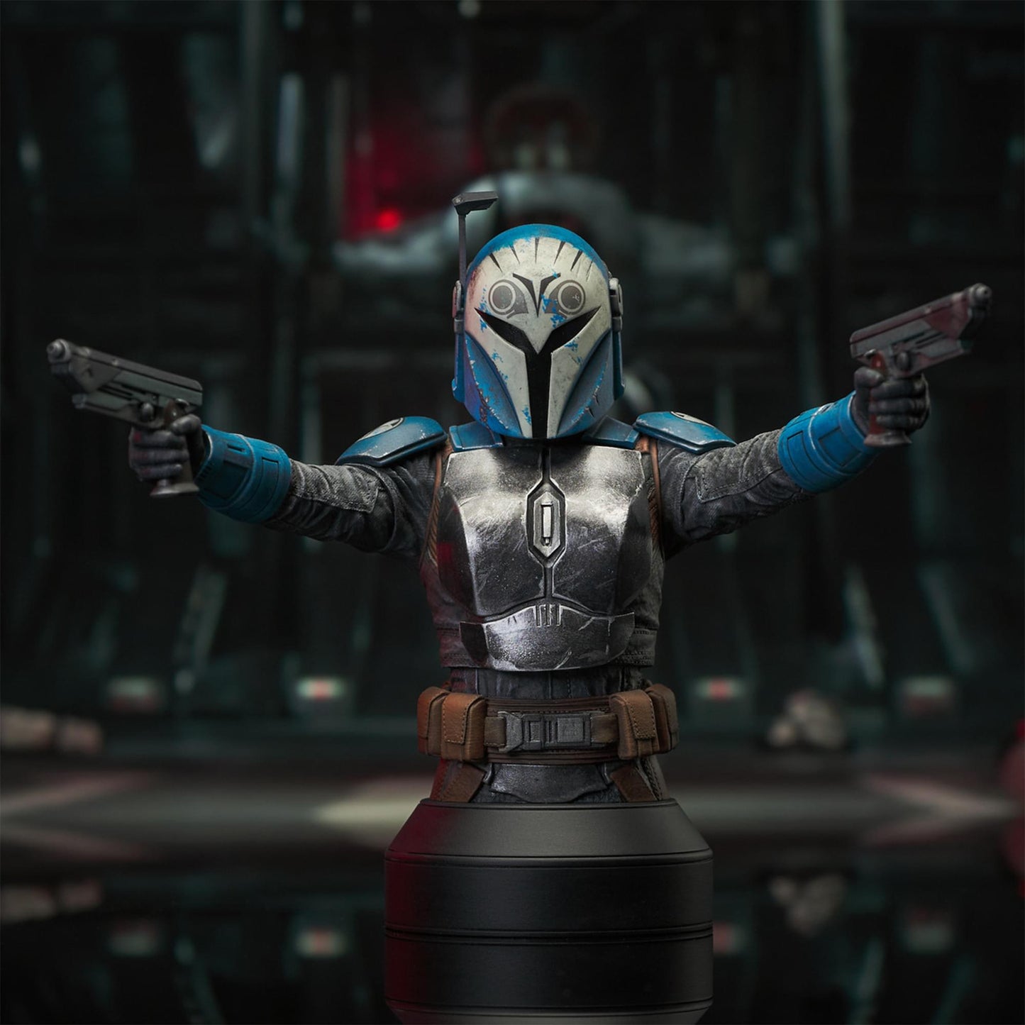 A resin bust depicting Bo-Katan Kryze in her Nite Owl armor, holding blasters in each outstretched hand. In the background is a hangar bay.