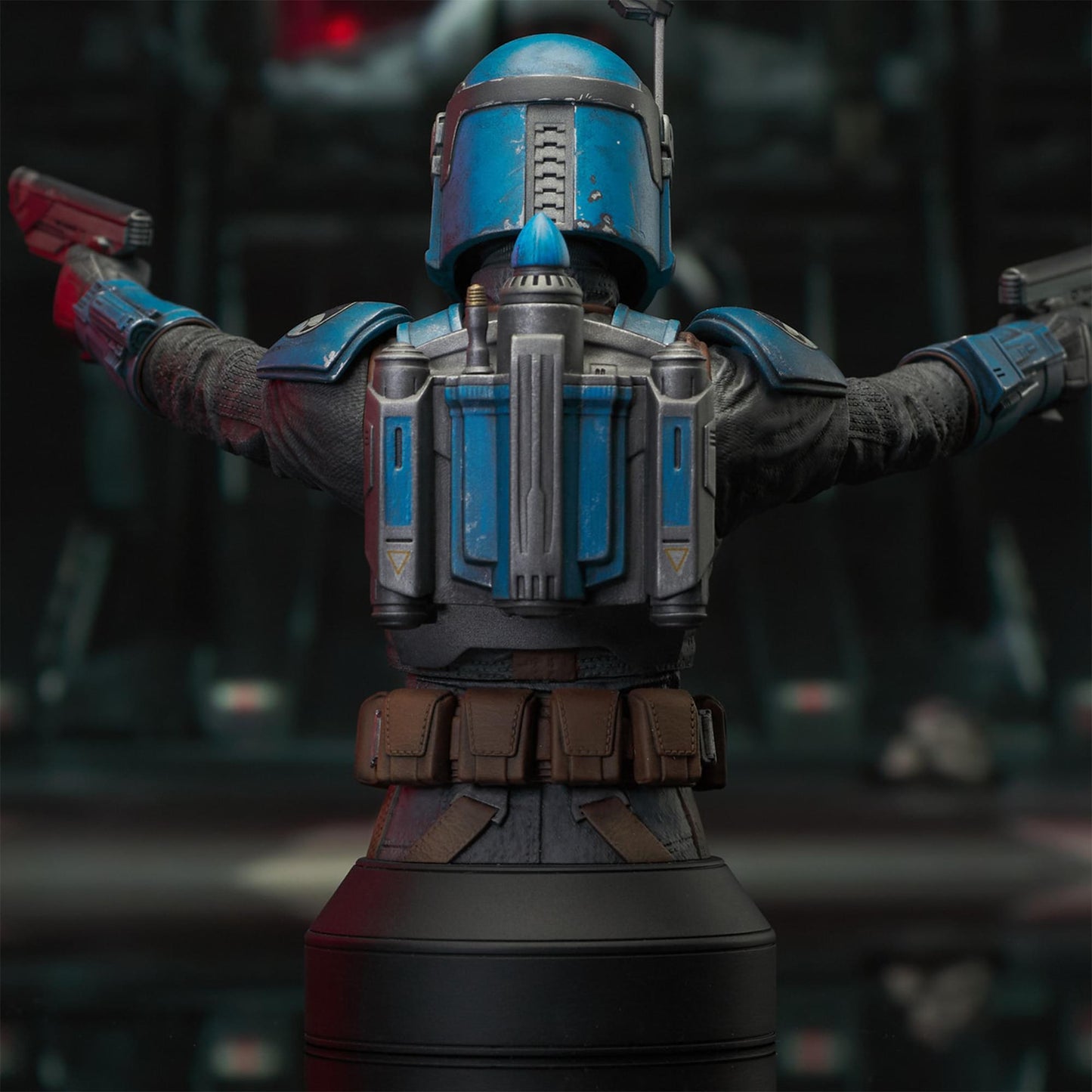 A resin bust depicting Bo-Katan Kryze in her Nite Owl armor, holding blasters in each outstretched hand. In the background is a hangar bay.