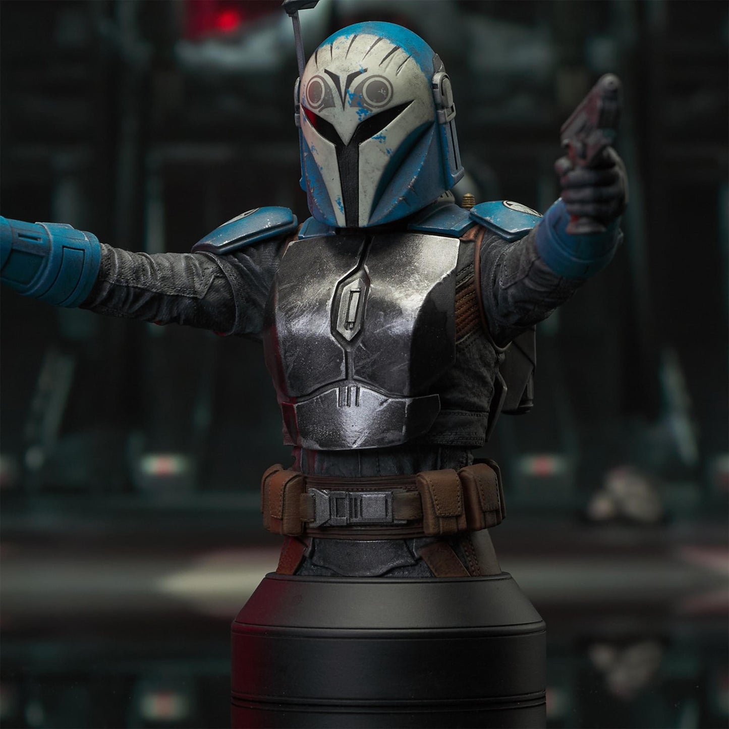 A resin bust depicting Bo-Katan Kryze in her Nite Owl armor, holding blasters in each outstretched hand. In the background is a hangar bay.