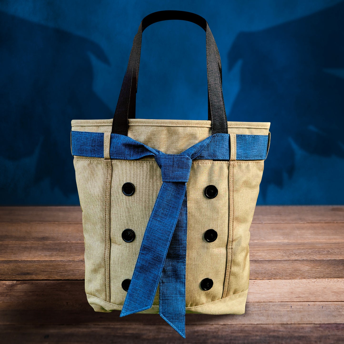 A khaki-colored tote bag with a blue necktie around the top, sitting on a wooden table. In the background is a blue wall with a shadow of angel wings behind the bag.