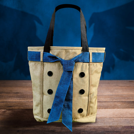 A khaki-colored tote bag with a blue necktie around the top, sitting on a wooden table. In the background is a blue wall with a shadow of angel wings behind the bag.