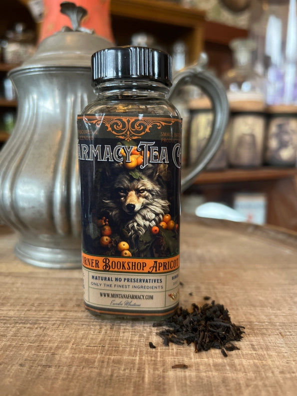 Bottle of Pharmacy Tea Co. tea with a wolf illustration on a wooden surface.