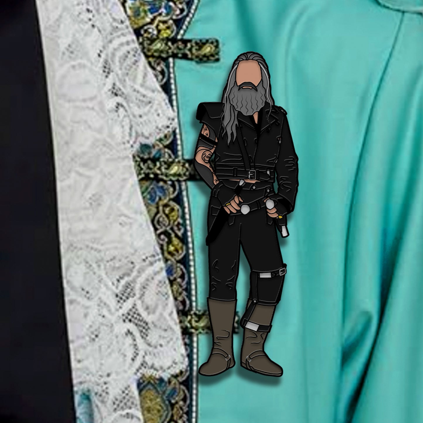 A pin depicting a pirate in dark clothes, against a light blue cloak.