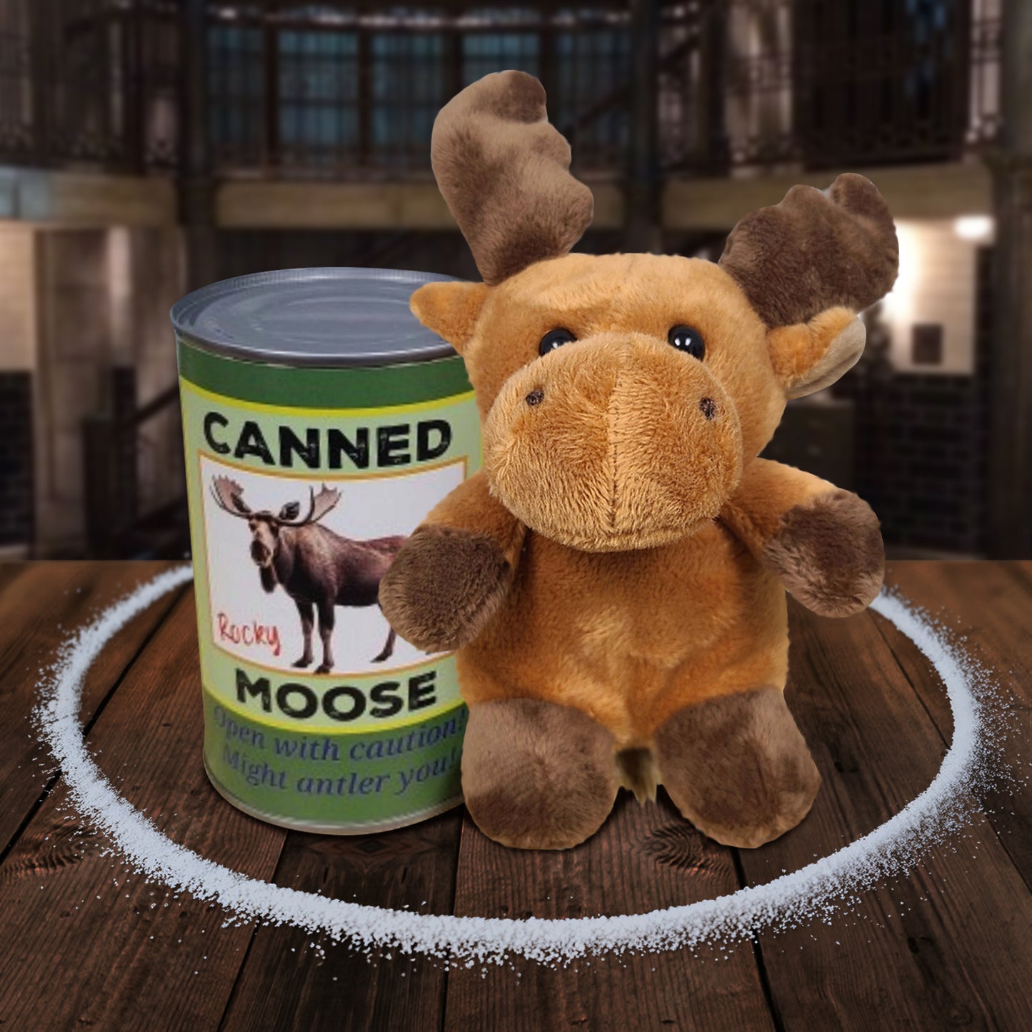 A moose plushie sitting next to a green can, on a wooden table. The front of the can has a picture of a moose, with black and blue text that says "canned moose. Open with caution! Might antler you!" A circle of salt surrounds the plushie and can. In the background is The Bunker.