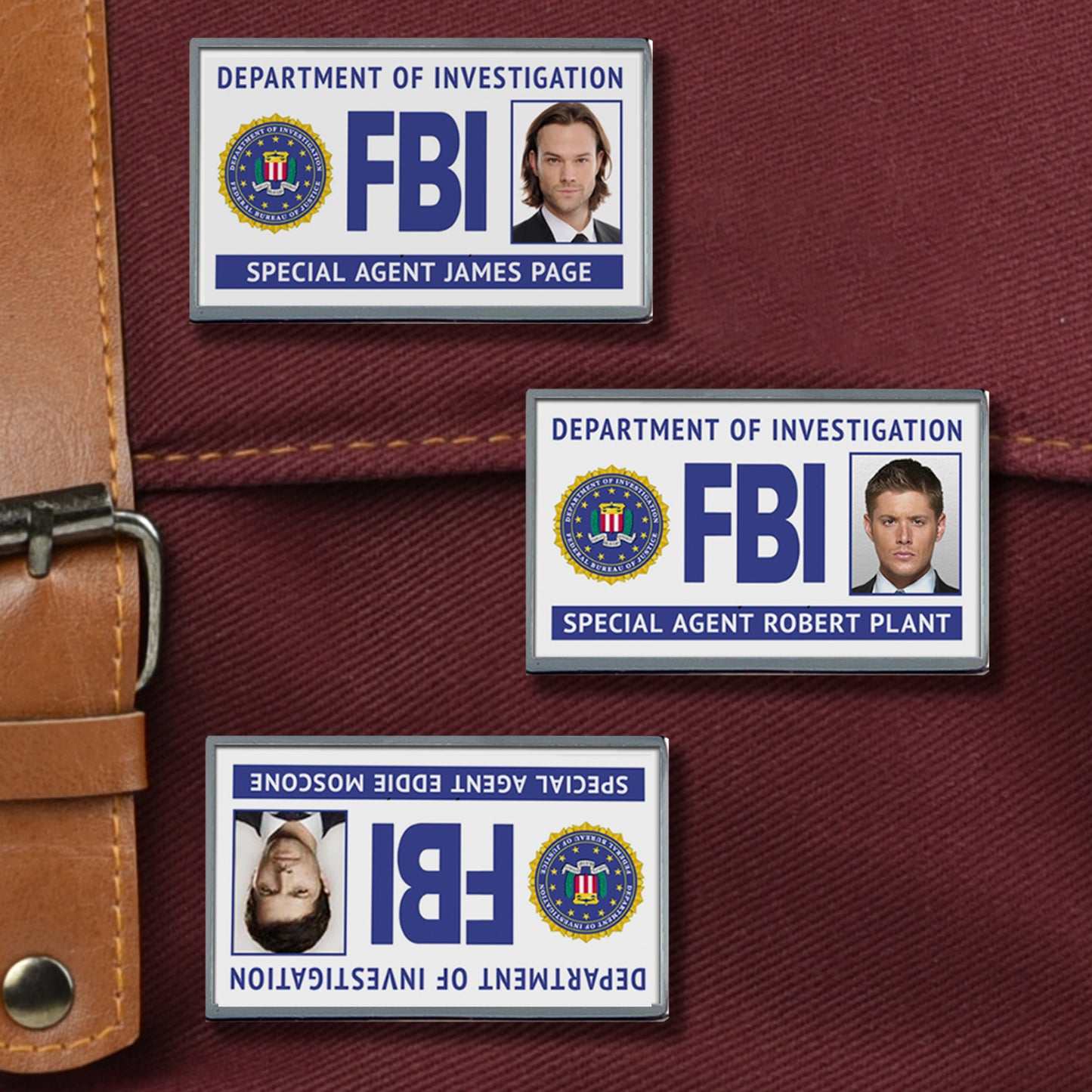Three enamel pins on a maroon canvas bag. The pins all depict fake FBI badges with Sam, Dean, and Castiel's faces in each. Castiel's badge is upside down.