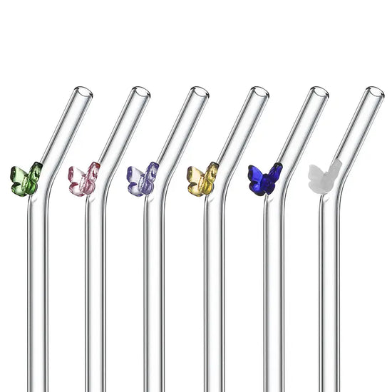 Six glass drinking straws against a white background. Each straw has a bend at the top, and a small glass butterfly is attached. Each butterfly is a different color.