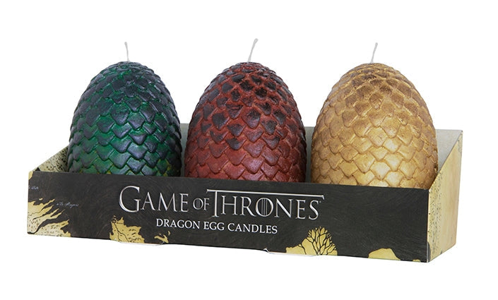 Three egg-shaped candles in a cardboard package. The eggs have scales around their outside. One is green, one is red, and one is gold. The package is black and gold, with silver text that says "Game of Thrones, dragon egg candles."