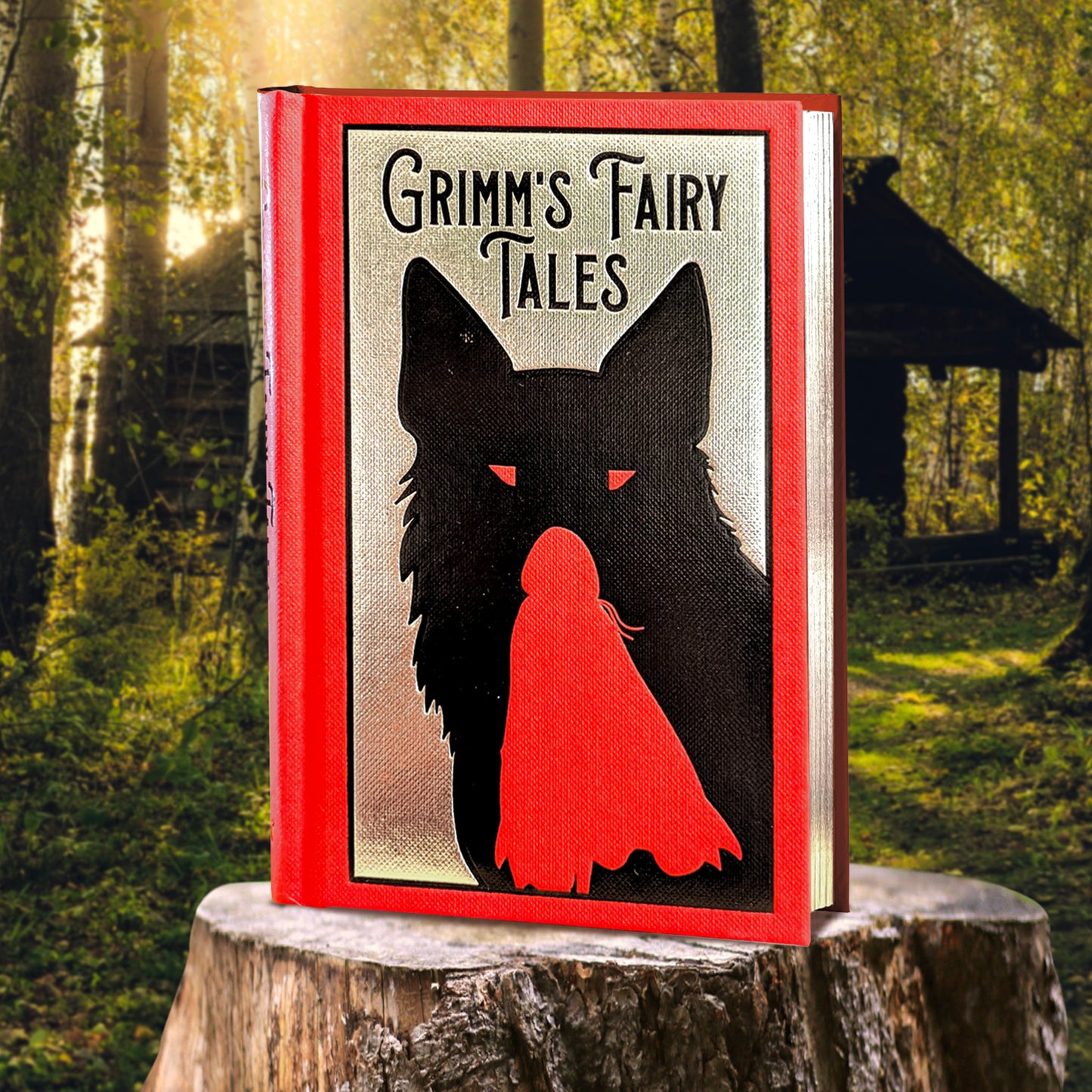 A red and black hardcover book on a tree stump. On the cover is a black silhouette of a large wolf, against a grey background. Inset in the wolf is a red silhouette of Little Red Riding Hood. Black text at the top says "Grimm's Fairy Tales." In the background is a rundown cabin in the woods.