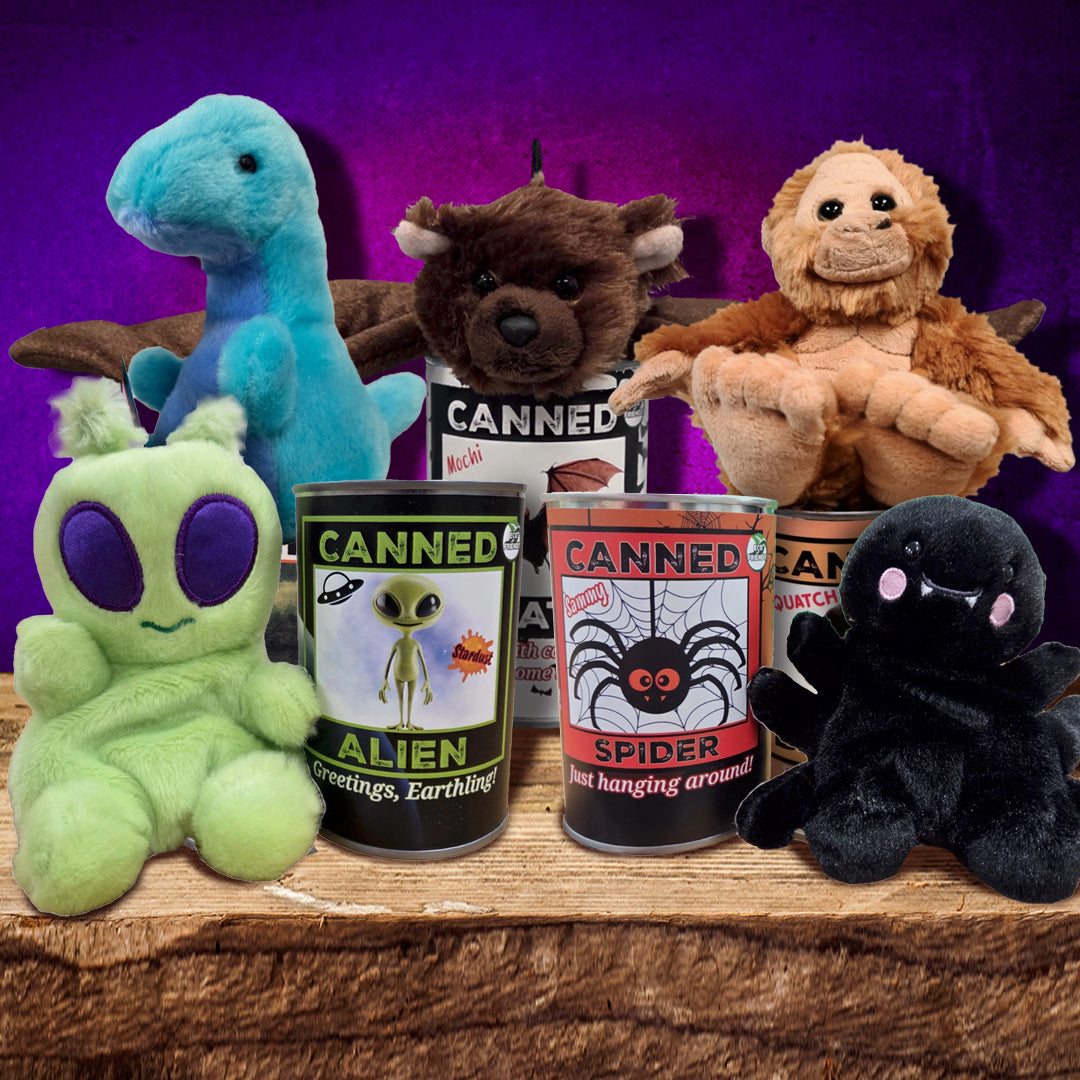 A collection of spooky stuffed animals on a wooden table. Next to them are cans with their pictures on the front.