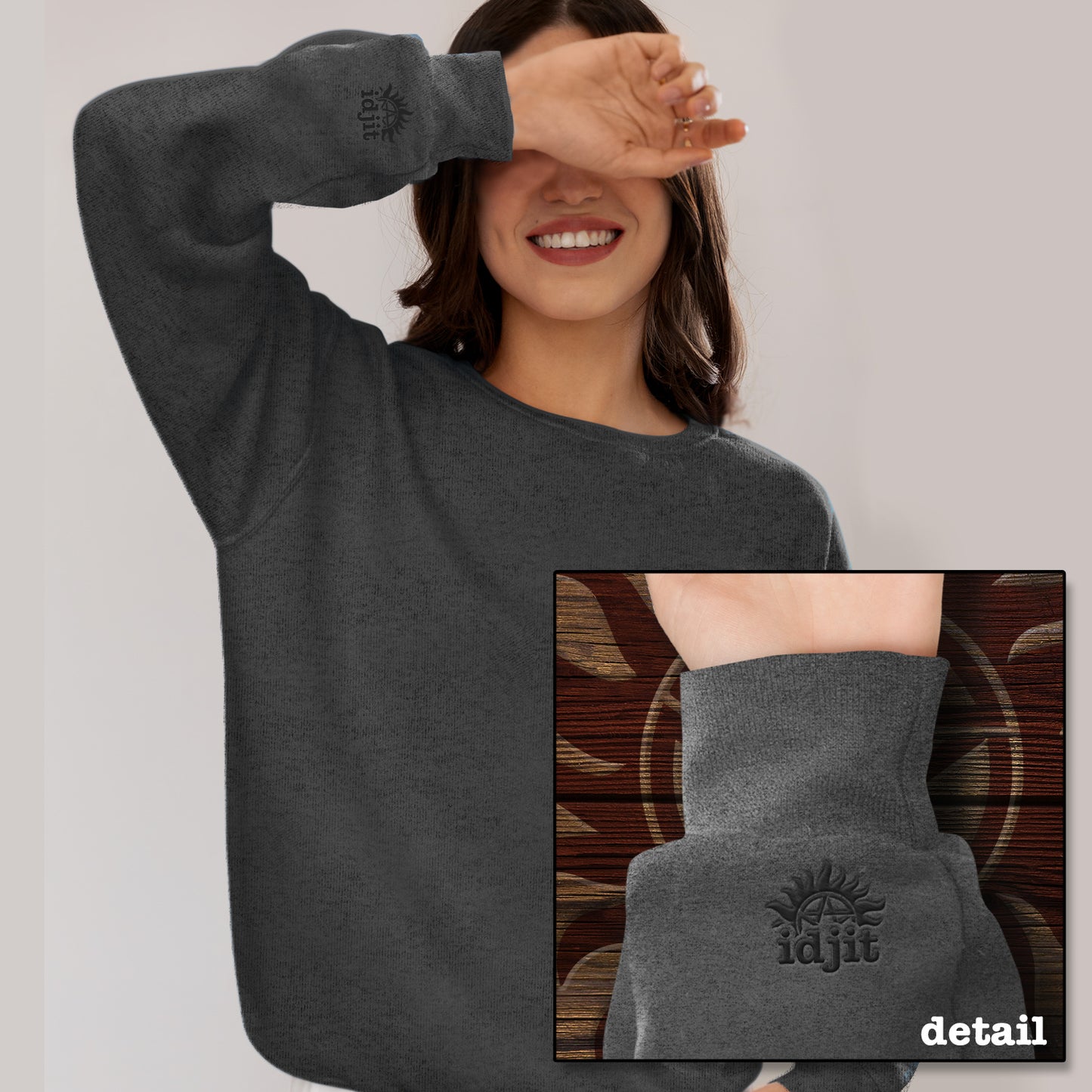 A model wearing a grey sweatshirt. An inset image shows the cuff which features an embroidered anti-possession symbol with "idjit" underneath