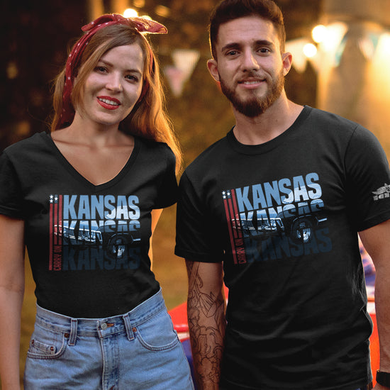 Two models side by side wearing black tee shirts. In the front of each shirt is blue text that says “Kansas Kansas Kansas,” with a black Chevy Impala superimposed on the text. On the left of the text are three red stripes with red text saying “carry on.”