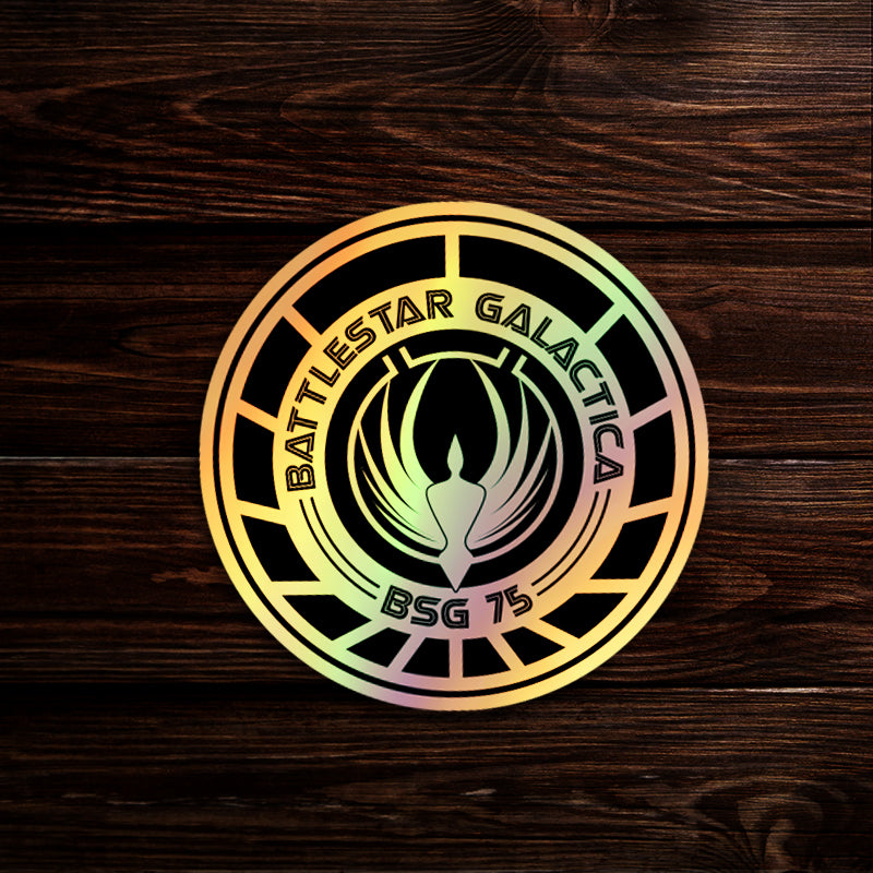 A round sticker depicting the Battlestar Galactica logo, on a wooden table