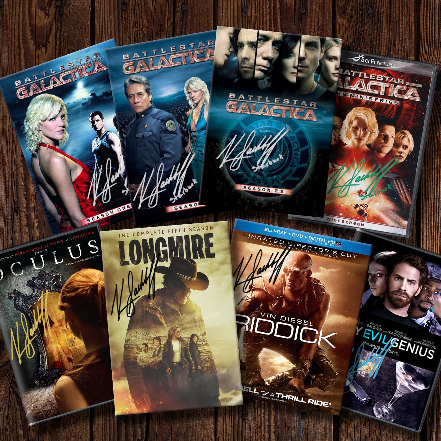 Collection of DVD covers from various movies and TV shows, all featuring Katee Sackhoff's autograph, on a wooden surface