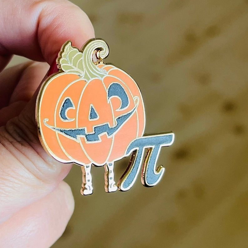 An enamel pin depicting a jack-o-lantern next to a Pi symbol