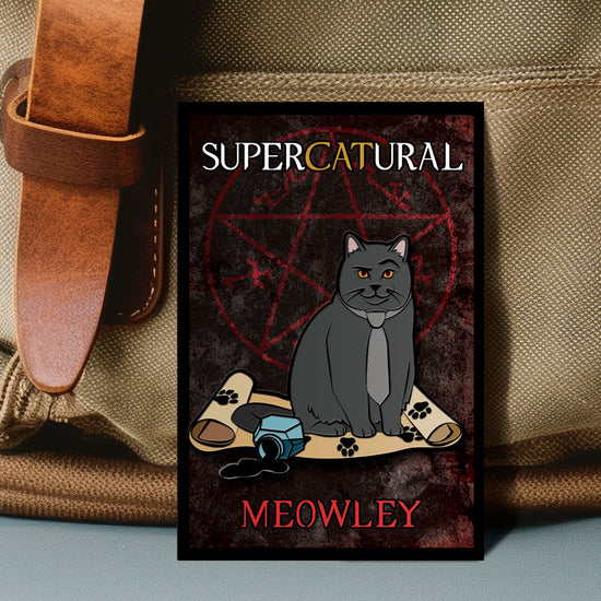 An enamel pin against a beige canvas bag. The pin depicts a chubby gray cat wearing a light grey necktie. Under the cat is a parchment scroll with black paws prints on it, next to a spilled bottle of ink. The background of the pin is a mottle red and black, with a red pentagram. White and yellow text says "Supercatural: Meowly"