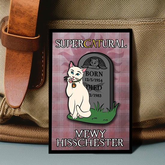 An enamel pin against a beige canvas bag. The pin depicts a white cat sitting in front of a gravestone, washing her paw. The gravestone has an image of a cat with angel wings at the top. The inscription shows the birth and death dates. White and yellow text says "Supercatural: Mewy Hisschester." In the background of the pin is a light purple plaid pattern.