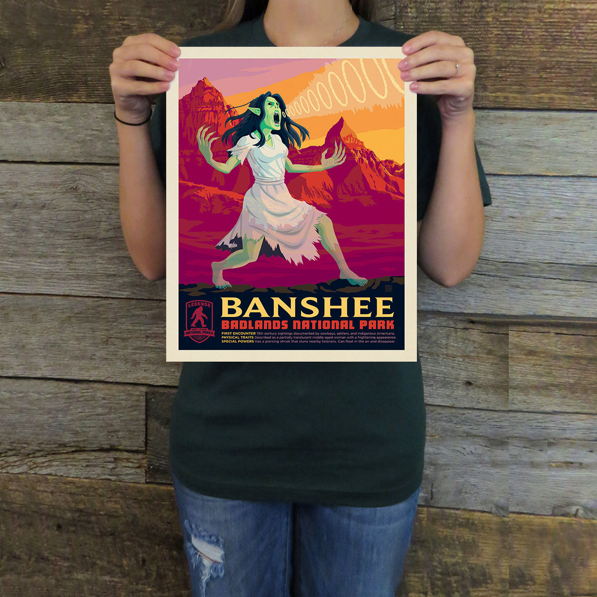 Person holding a poster of a banshee in a national park with a wooden background