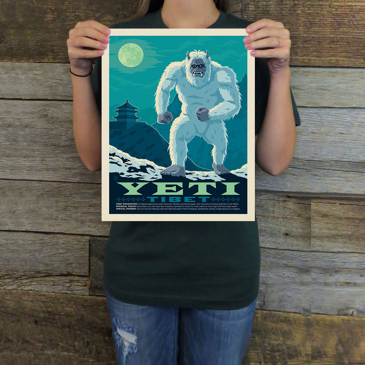 Person holding a poster of a Yeti with a mountain and moon background